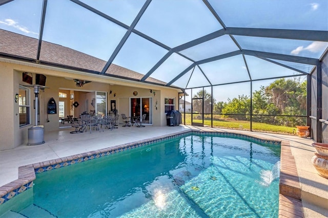 view of swimming pool with ceiling fan, a patio, and glass enclosure