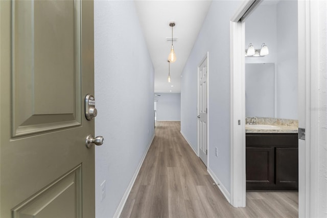 hallway with sink and light hardwood / wood-style flooring