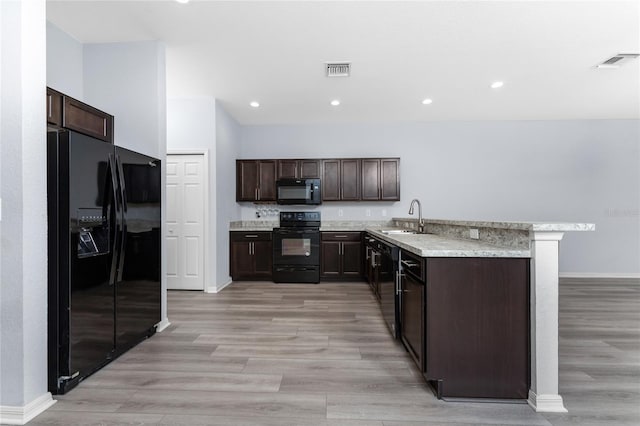 kitchen featuring dark brown cabinetry, sink, black appliances, and light hardwood / wood-style floors