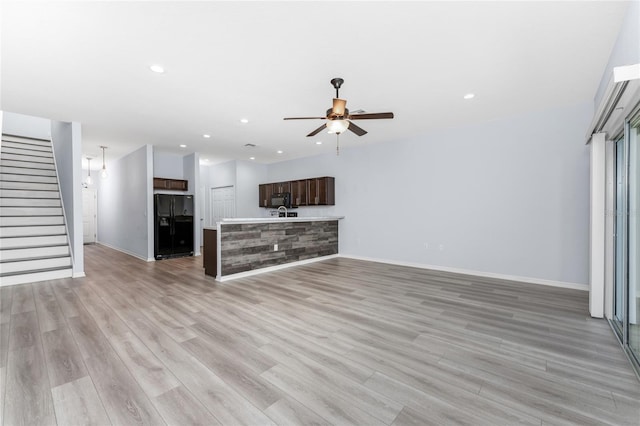 unfurnished living room featuring ceiling fan and light wood-type flooring