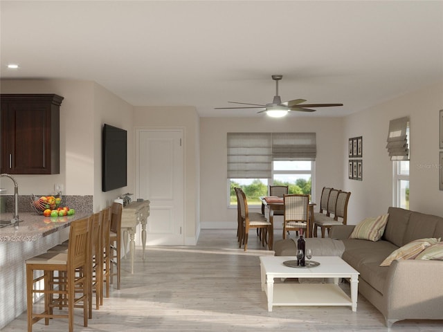 living room featuring sink, ceiling fan, and light wood-type flooring