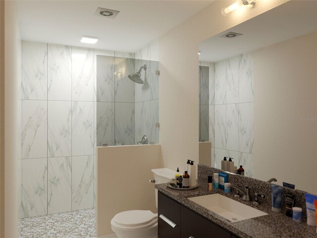 bathroom featuring vanity, tiled shower, and toilet