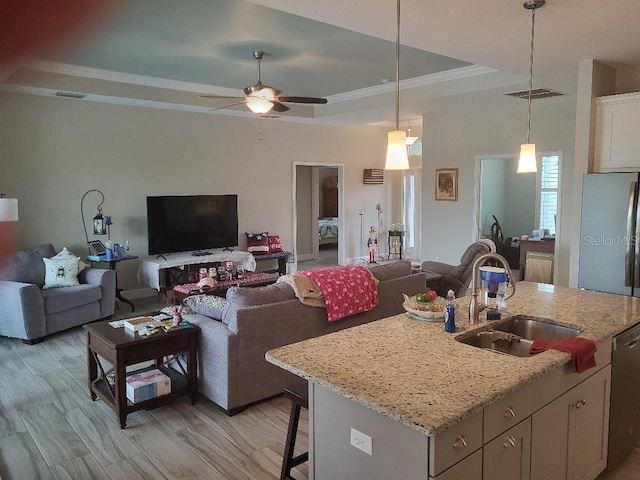 kitchen with sink, a kitchen island with sink, light wood-type flooring, a kitchen breakfast bar, and ceiling fan