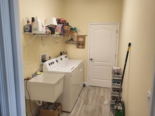 laundry area with separate washer and dryer, light hardwood / wood-style flooring, and sink