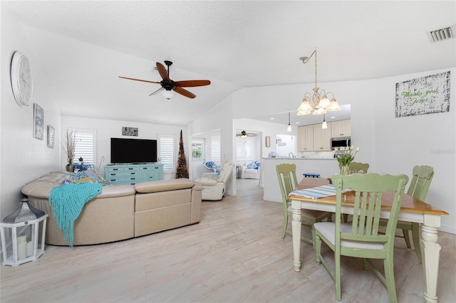 living room featuring ceiling fan with notable chandelier, lofted ceiling, and light hardwood / wood-style flooring