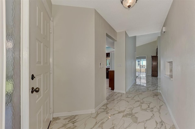 corridor with a textured ceiling and vaulted ceiling