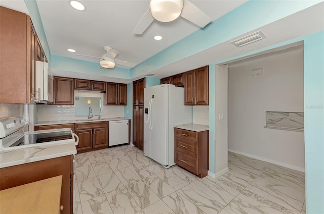 kitchen with ceiling fan, sink, light stone counters, backsplash, and white appliances