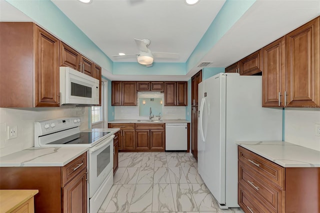 kitchen featuring ceiling fan, light stone countertops, white appliances, and sink