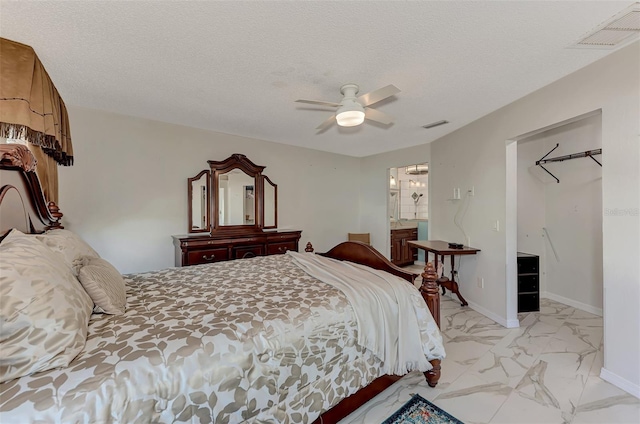 bedroom featuring ceiling fan, ensuite bathroom, and a textured ceiling