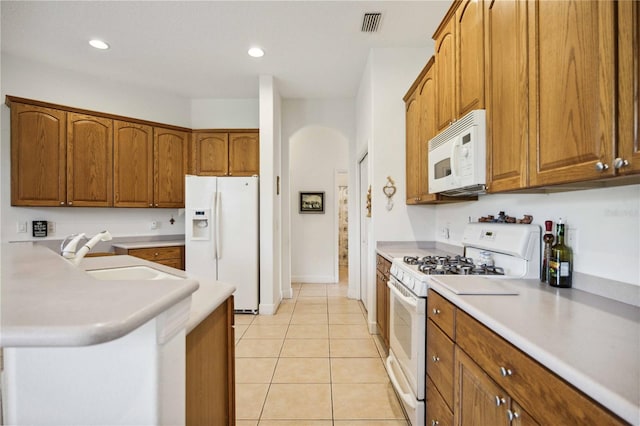 kitchen with light tile patterned flooring, white appliances, kitchen peninsula, and sink