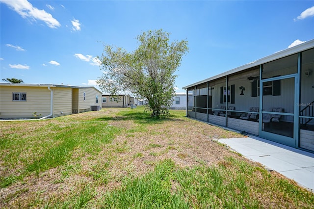 view of yard featuring a sunroom and ceiling fan