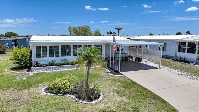 manufactured / mobile home with a carport, concrete driveway, and a front yard