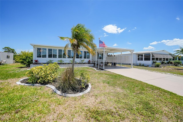 manufactured / mobile home with a carport, concrete driveway, and a front lawn