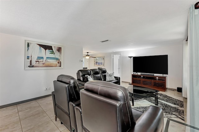 tiled home theater room with ceiling fan and a textured ceiling