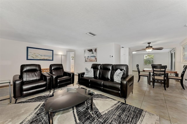 living room featuring ceiling fan, light tile patterned floors, and a textured ceiling