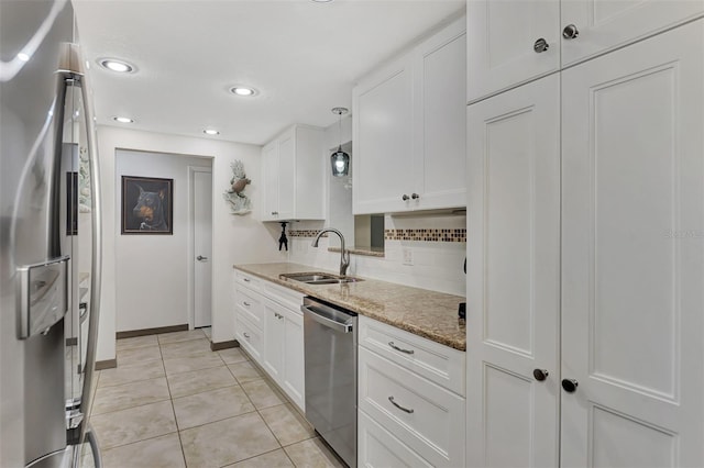 kitchen featuring hanging light fixtures, sink, appliances with stainless steel finishes, light stone counters, and white cabinetry