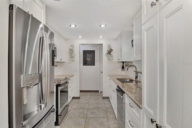 kitchen with light stone countertops, sink, white cabinets, and stainless steel appliances