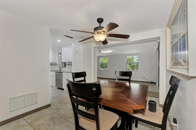 tiled dining area with ceiling fan, sink, and a textured ceiling