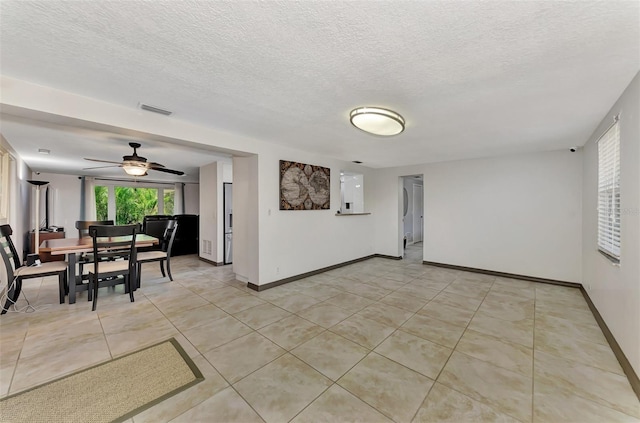 tiled empty room featuring ceiling fan and a textured ceiling