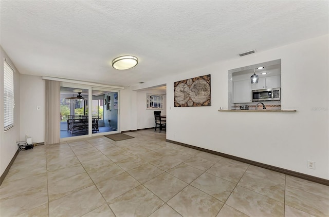 unfurnished room featuring light tile patterned floors, a textured ceiling, and ceiling fan