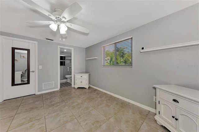 unfurnished bedroom featuring ceiling fan, light tile patterned flooring, and ensuite bathroom