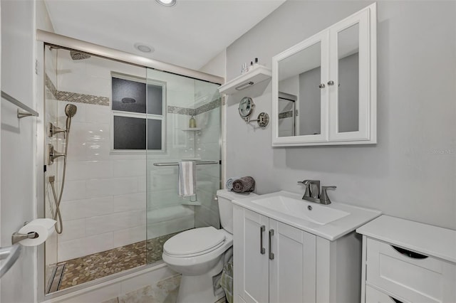 bathroom with vanity, toilet, and a shower with door