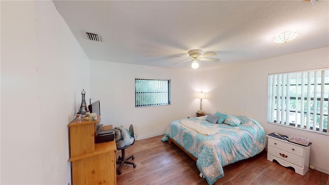 bedroom featuring ceiling fan, wood-type flooring, and a textured ceiling