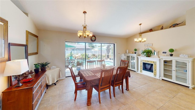 dining area with a tiled fireplace, light tile patterned floors, lofted ceiling, and a notable chandelier