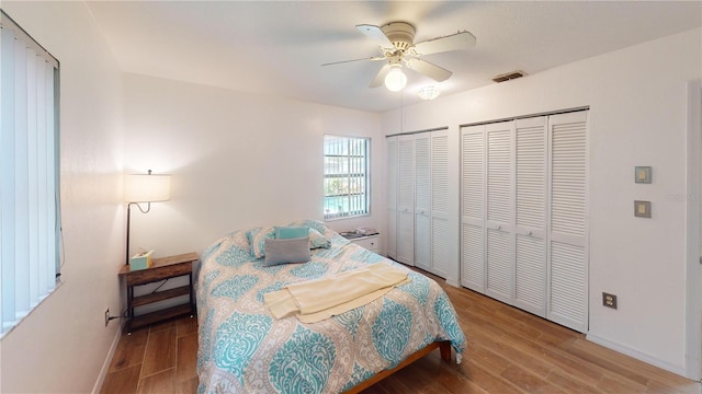 bedroom with multiple closets, ceiling fan, and hardwood / wood-style floors