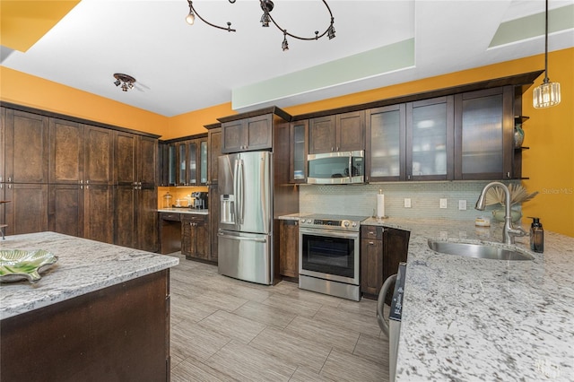 kitchen featuring light stone countertops, dark brown cabinetry, hanging light fixtures, and appliances with stainless steel finishes