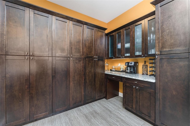 kitchen featuring dark brown cabinetry and light stone countertops