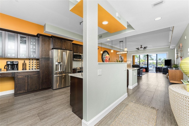 kitchen featuring decorative light fixtures, dark brown cabinets, light hardwood / wood-style floors, light stone counters, and stainless steel appliances