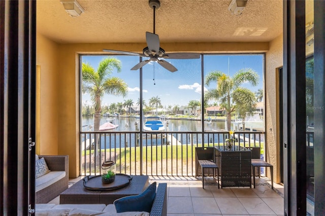 sunroom / solarium with ceiling fan, plenty of natural light, and a water view