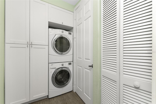 laundry room with cabinets and stacked washer / dryer