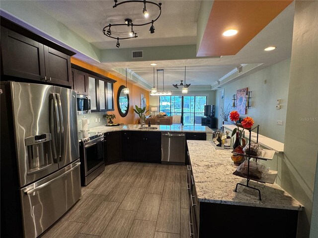 kitchen with kitchen peninsula, appliances with stainless steel finishes, light stone countertops, ceiling fan, and pendant lighting