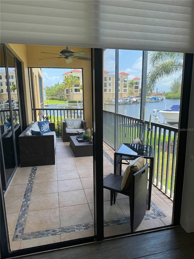 sunroom / solarium with ceiling fan and a water view