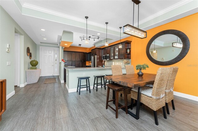 dining room featuring a raised ceiling, light hardwood / wood-style flooring, and ornamental molding