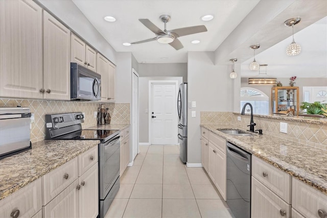 kitchen featuring light stone countertops, sink, stainless steel appliances, backsplash, and decorative light fixtures