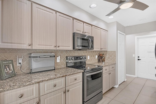 kitchen with light stone countertops, ceiling fan, stainless steel appliances, backsplash, and light tile patterned flooring