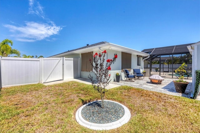 back of property featuring a lawn, glass enclosure, and a patio