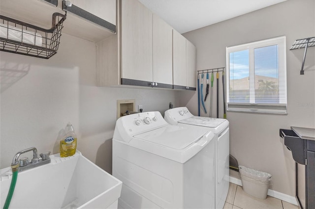 clothes washing area with washing machine and clothes dryer, sink, light tile patterned flooring, and cabinets