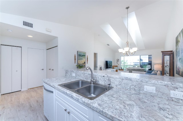 kitchen with white cabinets, white dishwasher, sink, vaulted ceiling, and a notable chandelier