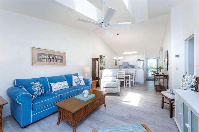 living room featuring ceiling fan with notable chandelier, light hardwood / wood-style flooring, and high vaulted ceiling