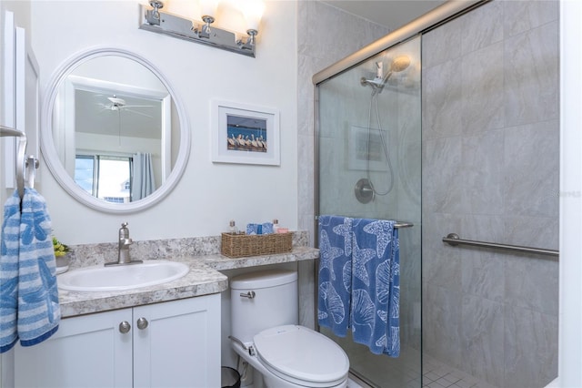 bathroom with ceiling fan, vanity, an enclosed shower, and toilet