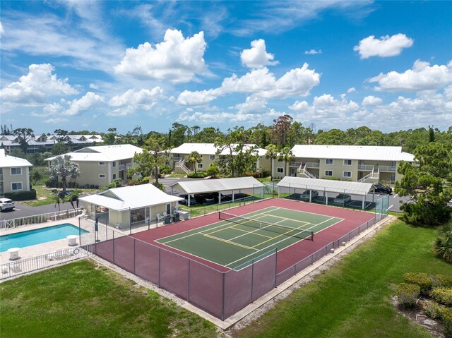 view of tennis court featuring a yard and a community pool