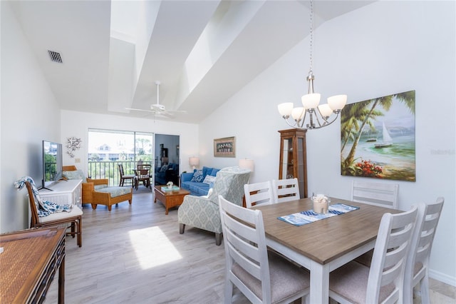 dining space with ceiling fan with notable chandelier, high vaulted ceiling, and light hardwood / wood-style flooring