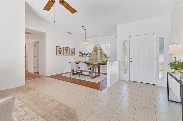 tiled foyer entrance featuring ceiling fan with notable chandelier and lofted ceiling