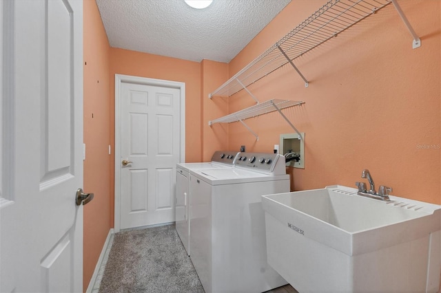 clothes washing area with washing machine and dryer, light carpet, sink, and a textured ceiling