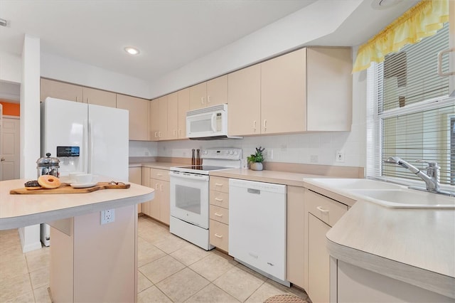 kitchen featuring cream cabinetry, light tile patterned floors, white appliances, and sink