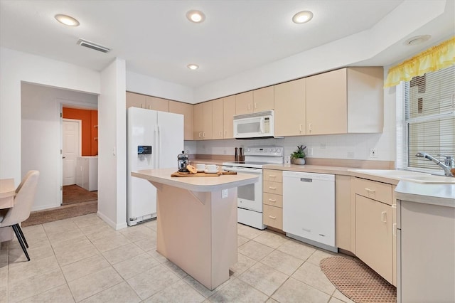 kitchen featuring white appliances, sink, washer / dryer, a kitchen island, and light tile patterned flooring